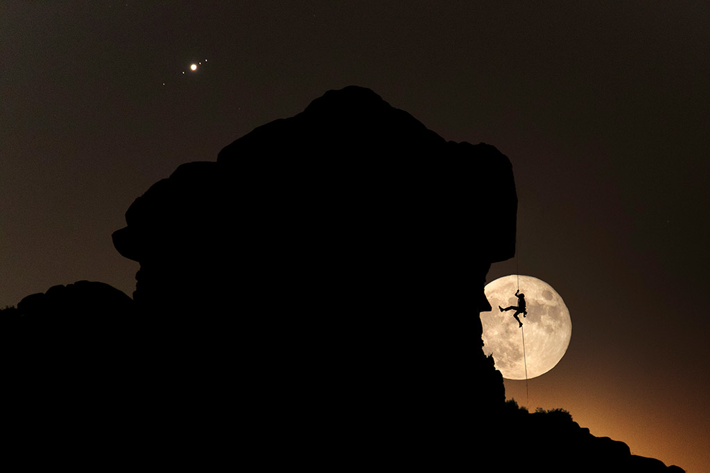 Full Moon and Jupiter with its moons over a climber silhouette in La Pedriza (Spain) by Dani Sanz