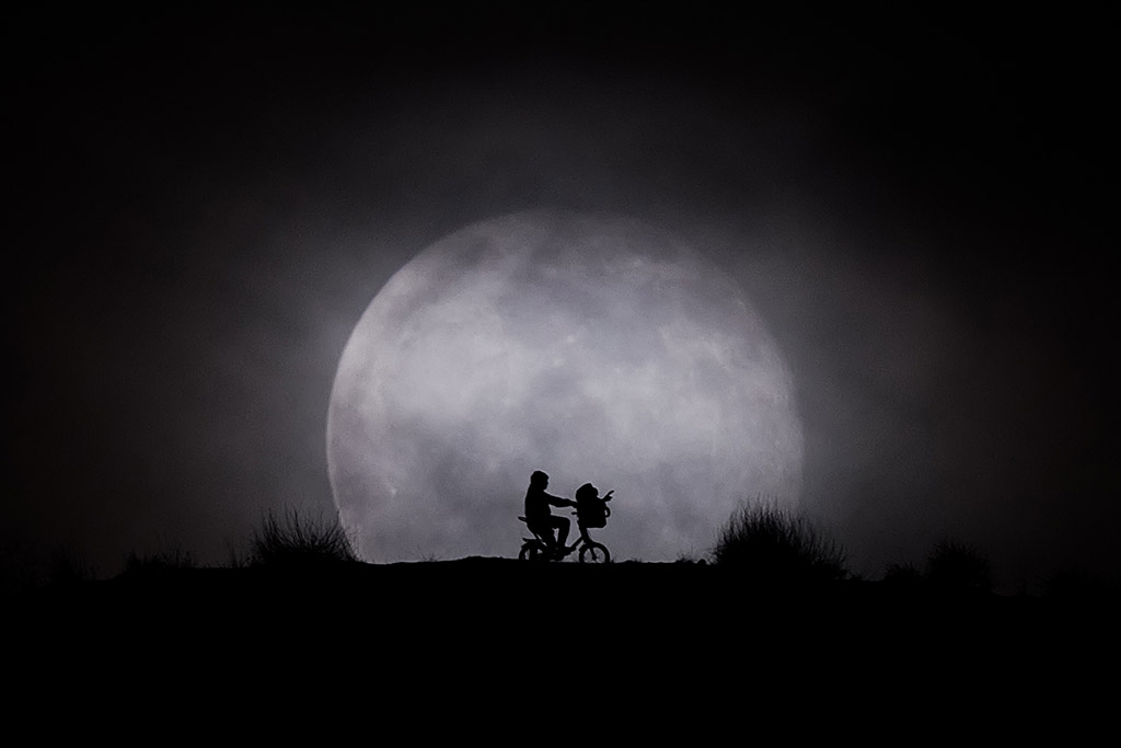 Elliott and E.T. silhouette behind a Full Moon (Madrid, Spain) by Kike Bustos